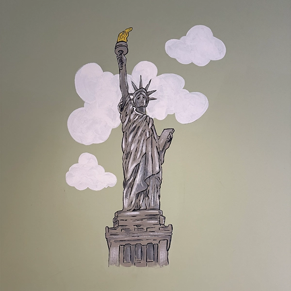A mural of the Statue of Liberty, holding a torch high, surrounded by fluffy clouds against a green wall backdrop.